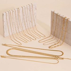 Collection of gold snake and blade chains displayed on elegant beige stone props