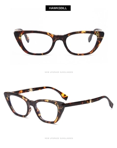 Detail of tortoise shell cat-eye sunglasses featuring golden metal hinges on white background