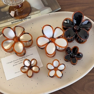 Set of six amber flower hair claws in black and white styles on a decorative plate