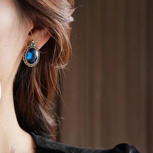 Détail de boucles d'oreilles vintage avec grandes pierres bleues ovales et monture dorée
