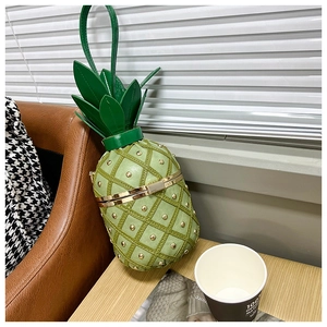 Close-up of green pineapple shaped crossbody bag with gold rivets and metal frame detail