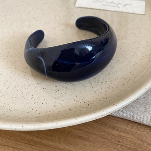 Detailed view of dark blue chunky acrylic bangle placed on a ceramic display plate