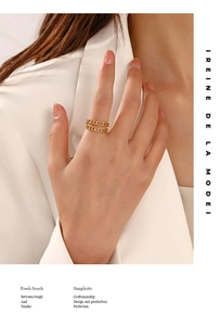 Detail view of a gold double-layer chain ring on finger with modern industrial texture