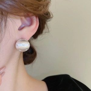 Macro detail of star-patterned pearl stud earrings worn on model's ear