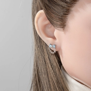 Silver bow earrings with light blue zircon and hanging chain fringe on a model