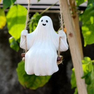 Close-up of a resin ghost sitting on a rope swing with a blurred garden background