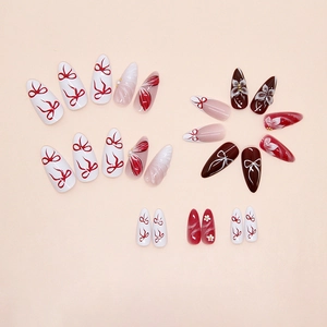 Detail of almond-shaped press-on nails with 3D floral and ribbon designs in a set
