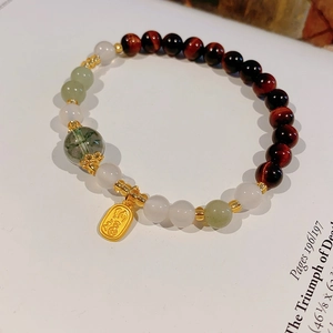Detail of beaded bracelet featuring red tiger eye, phantom quartz and Fu charm