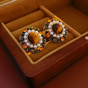 Detail of vintage bronze drop earrings with tiger eye stone and crystal accents