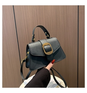 Detail of a vintage black leather handbag with a golden buckle and adjustable strap