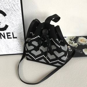 Detail of grey heart pattern on knitted bucket bag with black drawstring closure