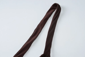 Détail du tissu en maille marron foncé et des fines bretelles d'une robe dos nu sexy