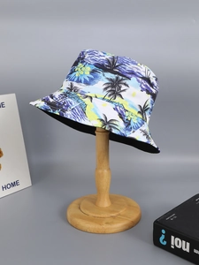 Detail of tropical palm tree and wave print on a double-sided sun hat displayed on a stand
