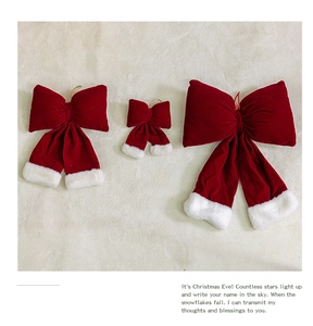 Three burgundy velvet Christmas bows with plush white edges in varying sizes on beige fabric