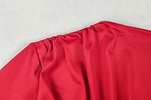 Detail of red ruched fabric on a slim fit dress showing texture and stitching