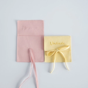Close-up detail of microfiber velvet jewelry pouches in pink and yellow with ribbon tie