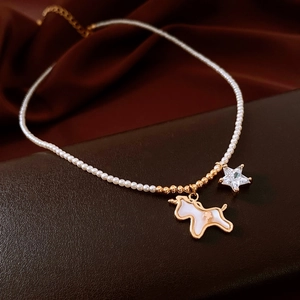 Close-up of 18K gold plated necklace with pearl chain, unicorn pendant and star detail