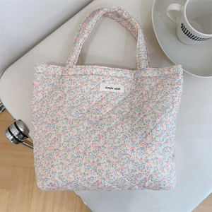 Detail of floral quilted cotton handbag with soft pastel patterns and brand label