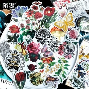 Macro shot of vintage floral stationery stickers with roses and butterflies on a white tray