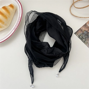 Detailed shot of black lace scarf with pearl accents on a white decorative table