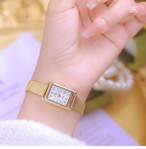 Close-up of golden rectangular quartz watch with Roman numerals on a woman's wrist