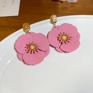 Détail de boucles d'oreilles fleurs roses avec base dorée et perle centrale blanche