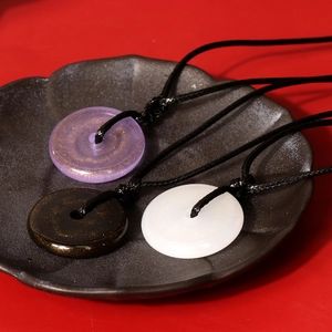 Close-up of three colorful resin safety buckle pendants in purple, black, and white