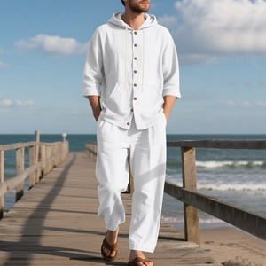 Detail of white linen hooded shirt and trousers set with wooden buttons on a beach