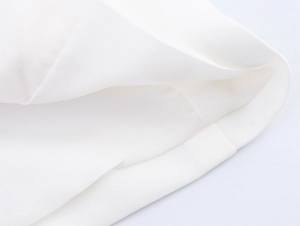 Gros plan détaillé sur la texture du tissu tissé blanc et les coutures de l'ensemble chic