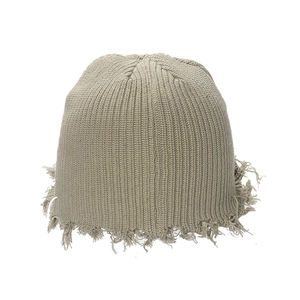 Detailed close-up of distressed knit beanie featuring fringe details and vintage textures