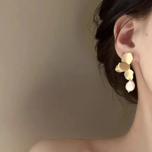 Elegant gold flower petal earrings with baroque pearl drop on a female model