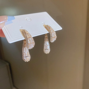 Macro detail of gold earrings featuring cubic zirconia paving and a stylish curved design