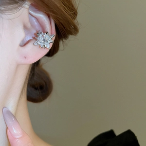 Close-up of a sparkling silver starburst ear cuff with zircon stones on a model's ear