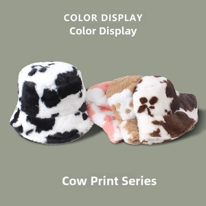 Détail des bobs en peluche à motif vache en noir, rose et marron pour l'hiver au chaud