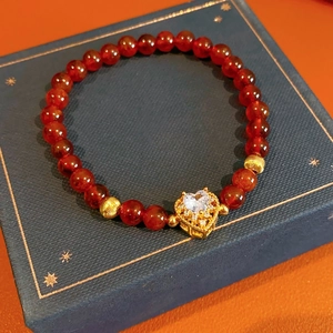 Detail shot of garnet beaded bracelet with golden heart pendant on luxury gift box