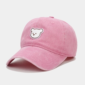 Close-up of pink cotton baseball cap featuring white bear embroidery on the front
