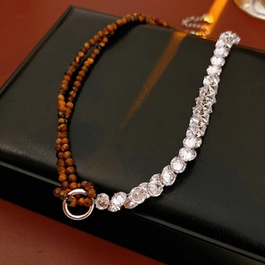 Detail of tiger eye stone and zircon heart necklace set with silver link on black leather