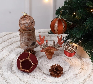Christmas tree ornaments in brown tones displayed on white faux fur with festive lighting