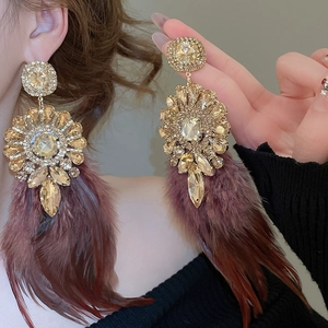 Gros plan de boucles d'oreilles bohèmes en plumes avec strass ambrés et plumes marron foncé