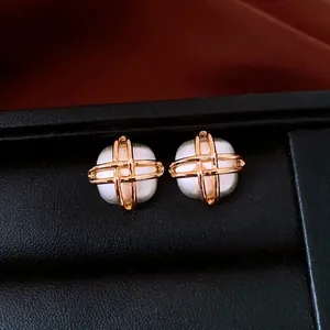 Square silver stud earrings with gold cross lines in a black jewelry box case