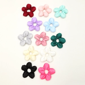 Flat lay of 12 colorful satin flower hair scrunchies on white background in various shades