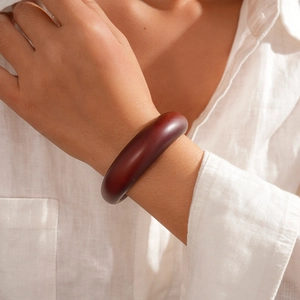 Detail view of a vintage dark reddish-brown acrylic geometric open bangle on model wrist