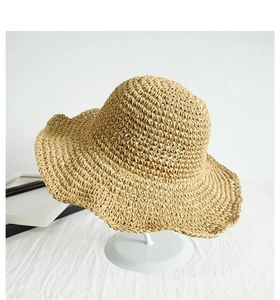 Detailed close-up of the woven straw texture and wavy brim of this summer sun hat