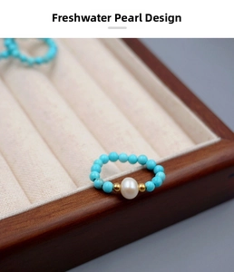 Detailed close-up of handmade freshwater pearl ring with turquoise beads and gold accents