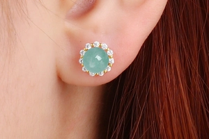 Detail view of round green jade stud earring with halo diamonds on model ear