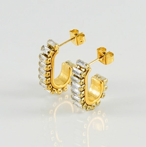 Detail of U-shaped gold earrings with rectangular zircon inlay and clear reflections