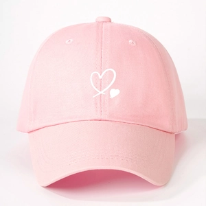 Close-up of a pink cotton baseball cap featuring a white embroidered heart on the front