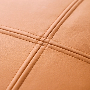 Macro view of light brown technical fabric with detailed cross-stitch seams on a pillow cover
