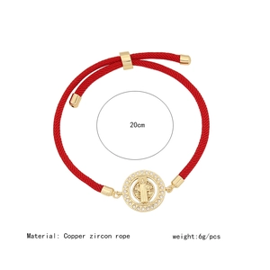 Macro detail of red string bracelet with 18K gold plated Saint Benedict medal and zircons