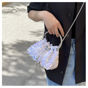 Detail of a sparkling sequin bucket bag with round metal handle and long chain strap